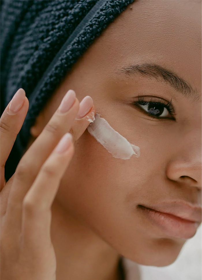 Een afbeelding van een vrouw die een product op haar huid aan het smeren is.